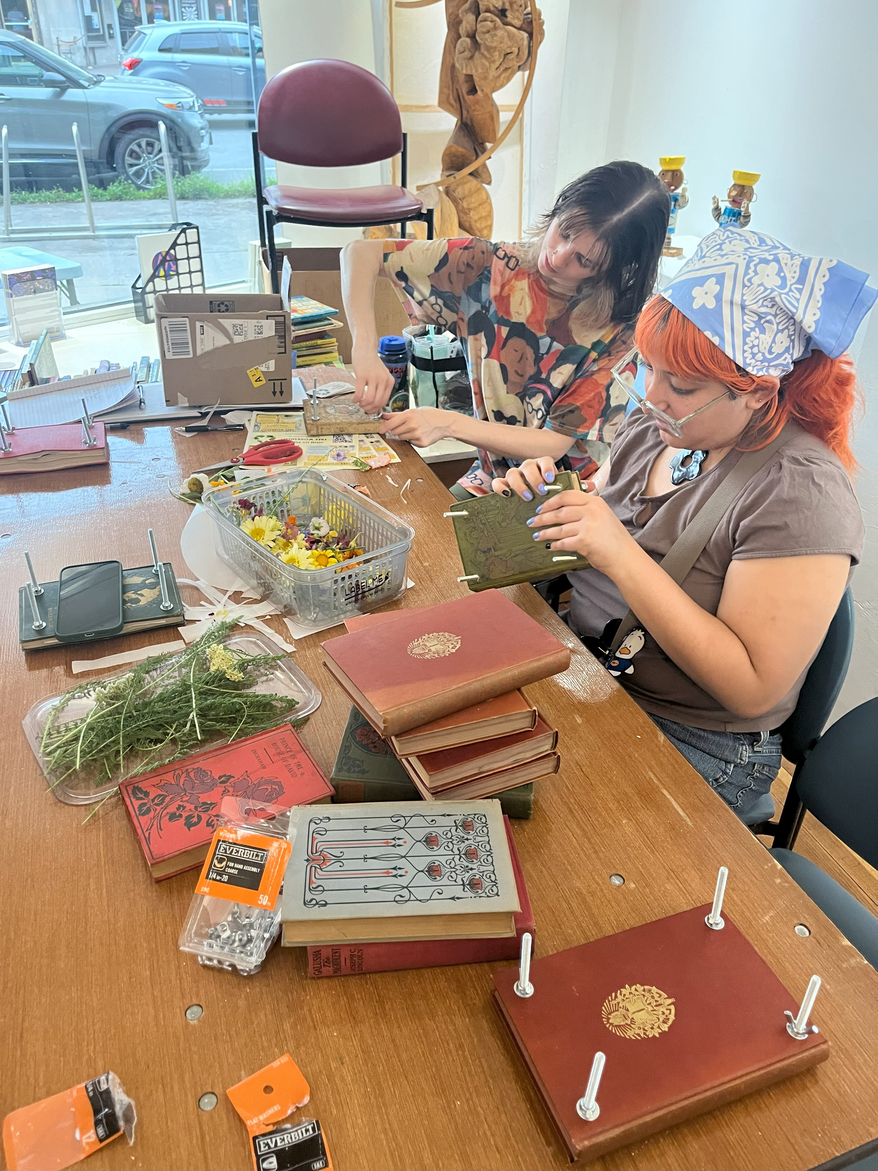 Two women upcycling books into flower presses