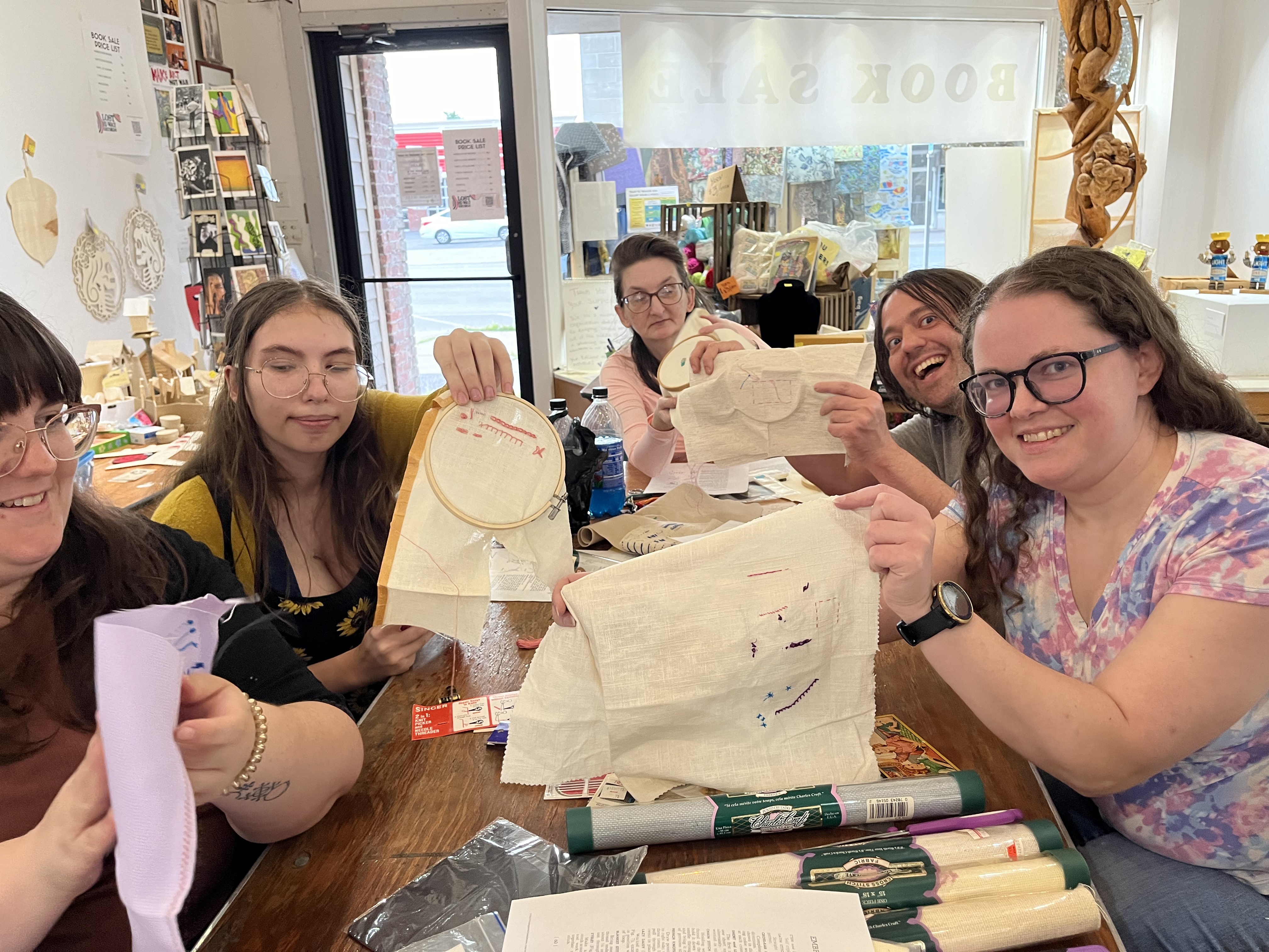 Students hold up embroidery work