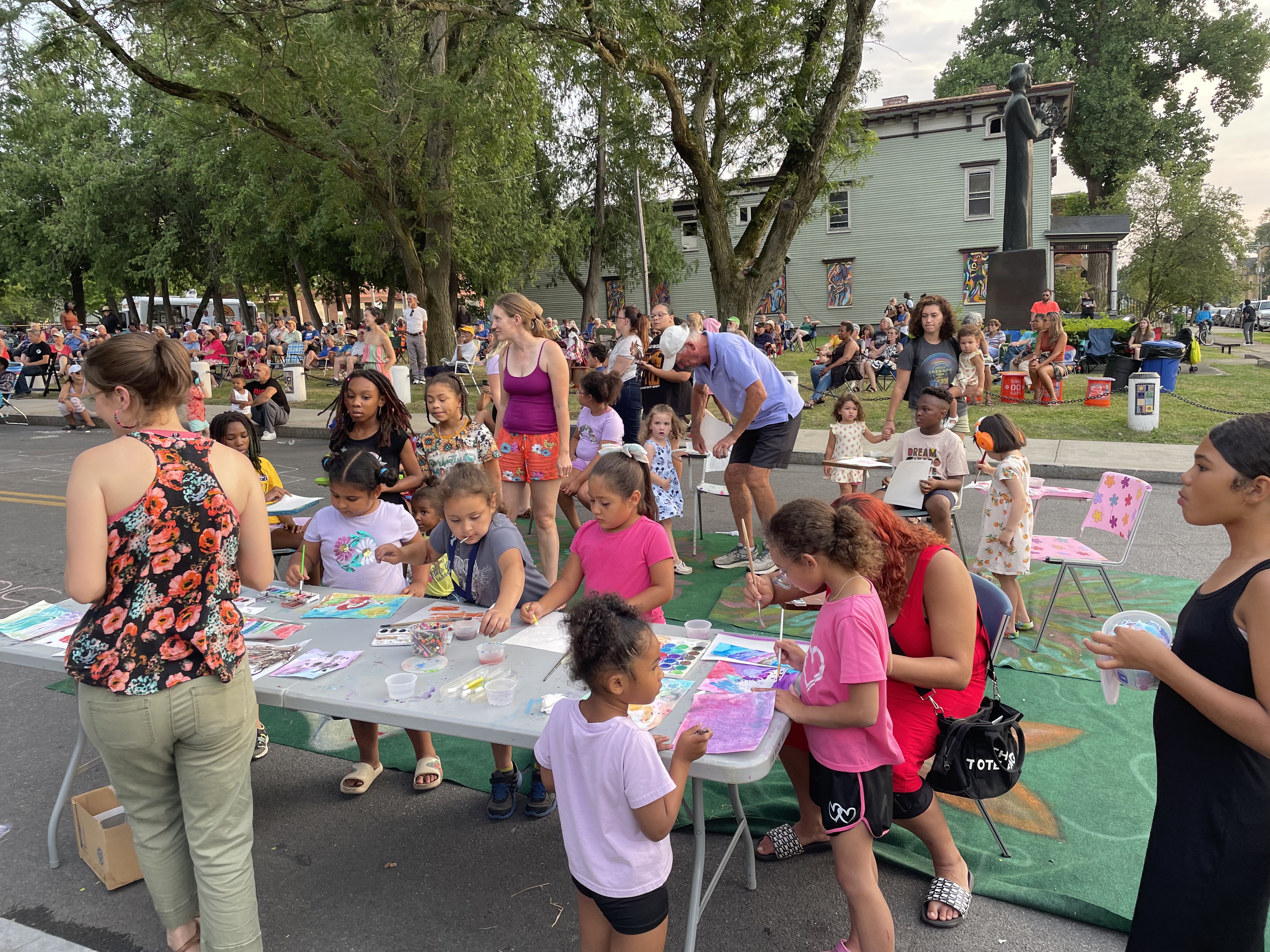 Kids making watercolor paintings at an outdoor concert